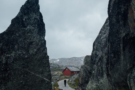 A cyclist on a gravel road that runs straight through a split between a big rock formation