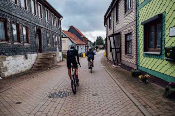 Two gravel cyclists passing through a quiet village street in the Harz Mountains.